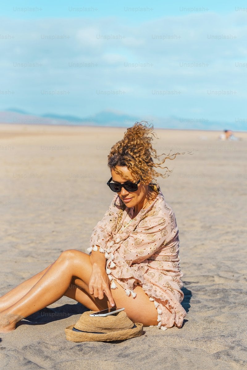 Female tourist relax under the sun in summer holiday vacation day at the  beach using mobile phone. Attractive adult woman enjoy connection outdoors.  Free solo single lady people in tourism activity photo &ndash;