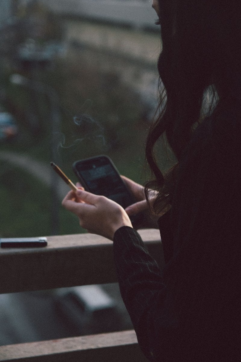 Woman Using Cellphone and Holding a Cigarette &middot; Free Stock Photo