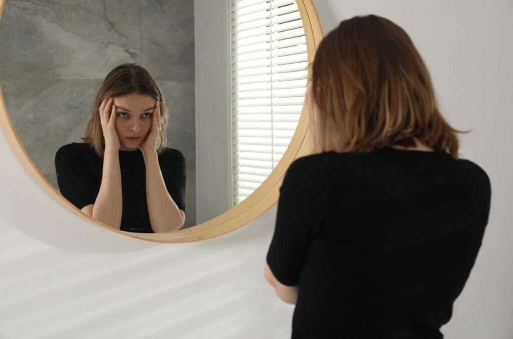 depressive frau seteht vor einem spiegel