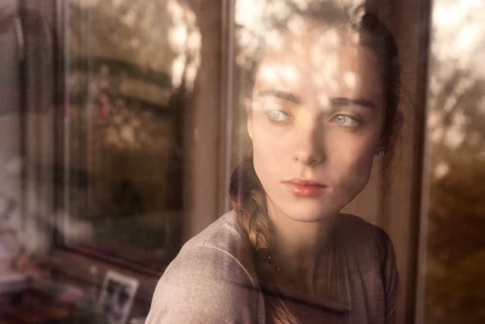 eine sch&ouml;ne traurige Frau, die aus dem Fenster schaut