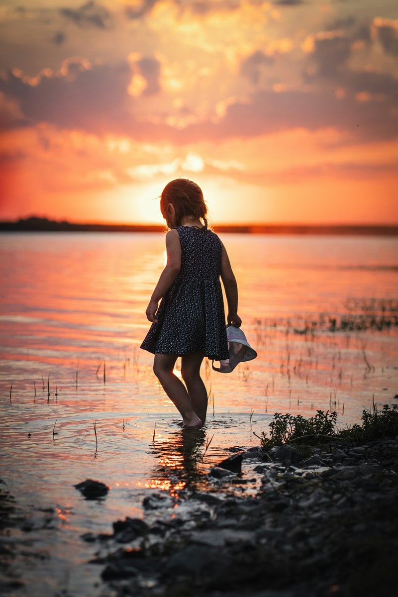 A little girl standing in the water at sunset - Free Photo on Unsplash