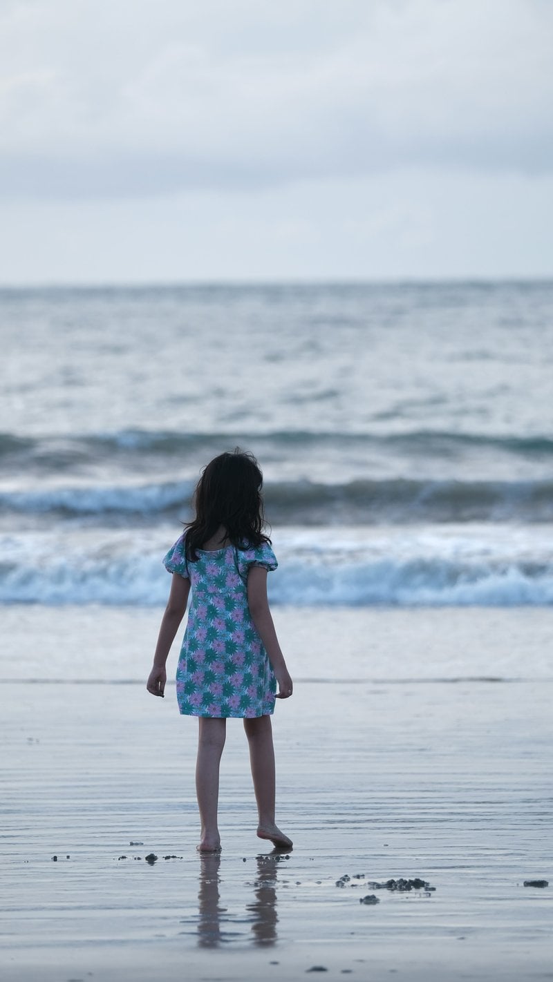 A little girl standing on top of a beach next to the ocean - Free Photo on  Unsplash